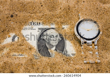 One dollar and watch in sand