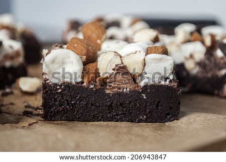 Profile view of a brownie topped with almonds, dark chocolate and marshmallows