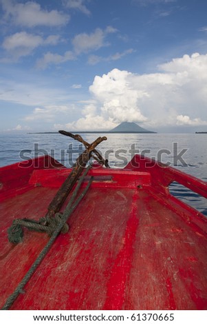Pulau Manado Tua with clouds as seen from the bright red bow of a dive boat in North Sulawesi, Indonesia.