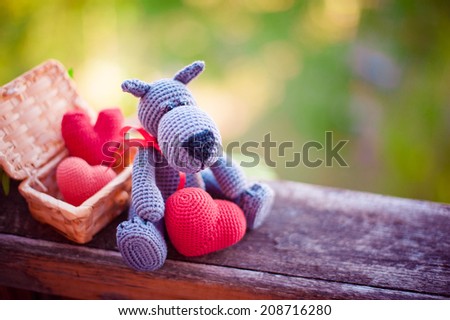 Knitted toy wolf with red hearts on bench