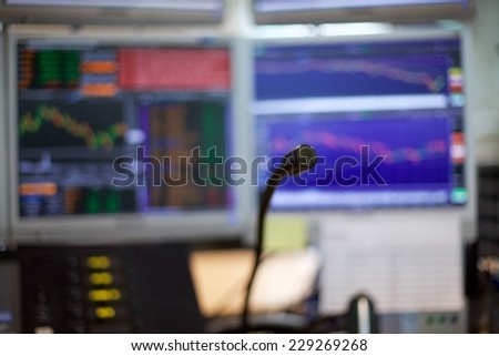 A microphone shot of a special phone system on trading floors.  In the background there is a blur image of monitors with trading graphs, charts and headlines.