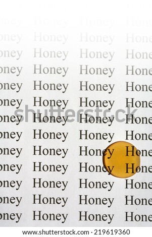 Words Honey typed on paper with a large drop of honey with white gradation
