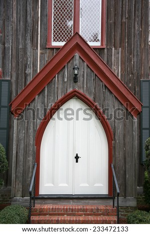white church door with red trim and unique shape dark handle