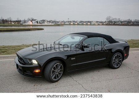 COLUMBUS, OHIO - CIRCA DECEMBER 14, 2014: A black 2014 Ford Mustang GT convertible idle on road near lake at sunrise.