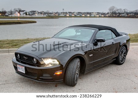 COLUMBUS, OHIO - CIRCA DECEMBER 14, 2014: A black 2014 Ford Mustang GT convertible idle on a road near lake at sunrise.
