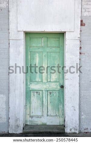 rustic warehouse door painted green against white exterior