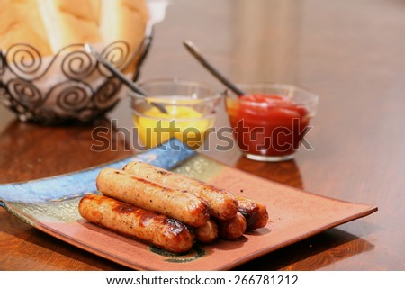 Grilled brats on a stacked on a plate ready to serve with condiments ketchup and mustard and buns ready
