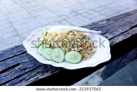 fried rice on white plate on timber log
