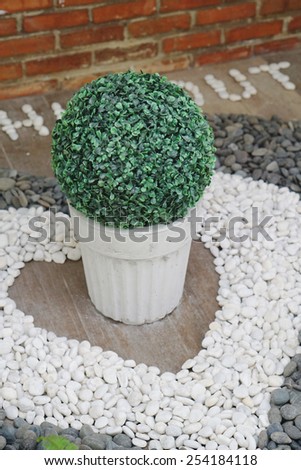 Fake plants in white pot on the floor with decoration pebbles