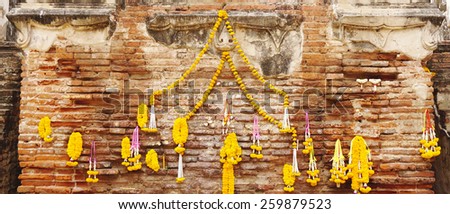 Flower lei hanging on the brick wall to worship in buddhist offering to god