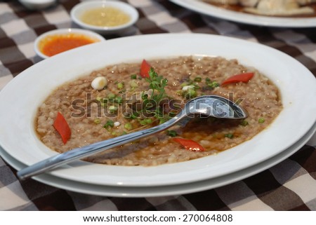 Asian style streamed mince pork with salted fish and soy sauce serving in white plate and stainless steel spoon