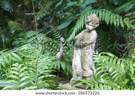 closed up of the Angle stone sculpture decoration item in the garden with fern leaves