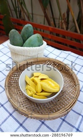 yellow mangoes ready to eat in the bowl and basket  with green mangoes background
