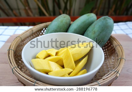 yellow mangoes ready to eat in the bowl and basket  with green mangoes background