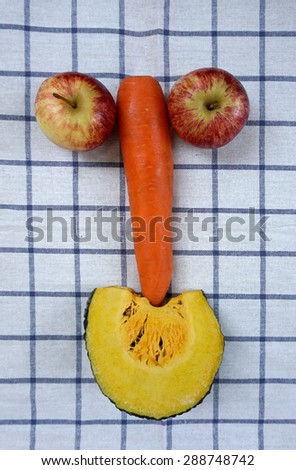 top view of fruits and vegetables arrange in smiling face on plaid fabric background
