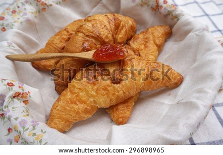 Croissants in the basket with flower pattern napkin with strawberry jam