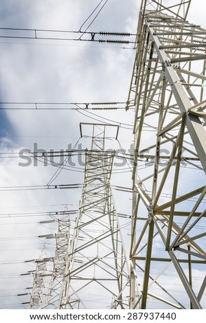 white supports of high-voltage power lines against the blue sky