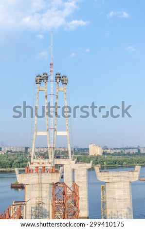 the construction of a bridge across the river with the supports, structural elements, cranes