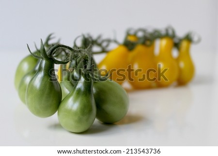 Organic green and yellow tomatoes on a light background. Unusual pear shape.