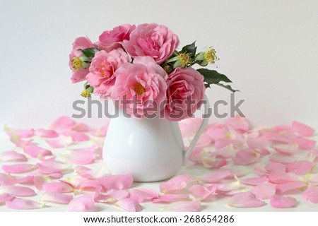 Bouquet of pink roses in a vase. Romantic floral still life with roses and petals.