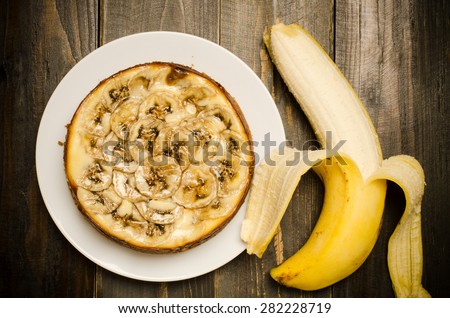 Homemade banana caramel cheesecake on wooden background