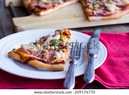 pizza with sausage, chicken, corn and cheese, fork,  knife