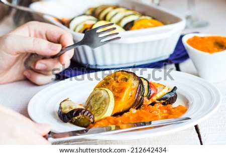 processes food vegetable ratatouille with a fork and knife, hands on a white background