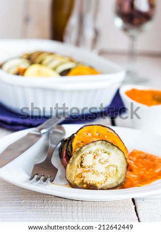 warm ratatouille sauce served in a round plate, fork, knife