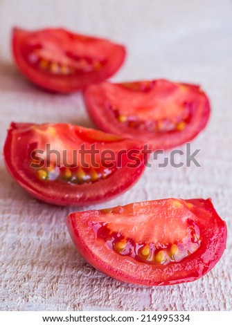 quarters of red tomatoes on a white wooden board, raw vegetables, vegetarian cuisine