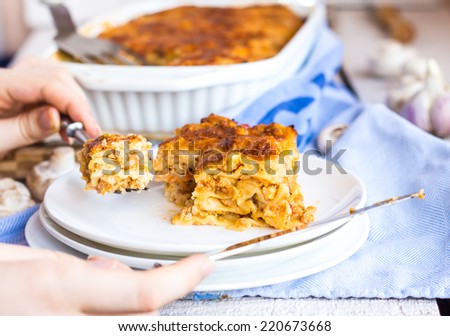 processes food meat lasagna on white plate, hands, Italian food
