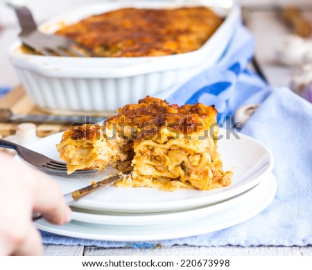 processes food meat lasagna on white plate, hands, Italian food