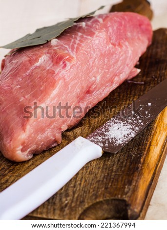 raw meat on a cutting board with spices, knife on a wooden board