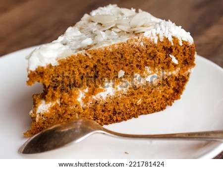 section of honey cake with whipped cream on a wooden board, closeup