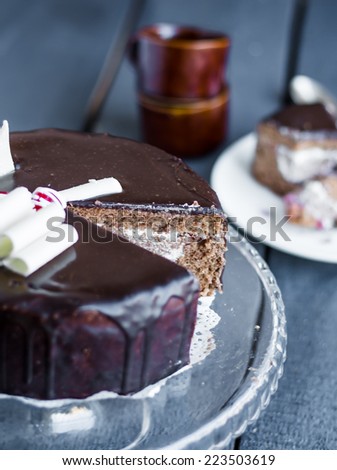 section of chocolate cake with cream and cherry on the stand, on a wooden board