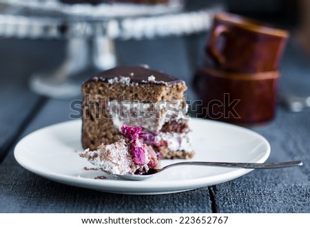 eating chocolate cake with butter cream and cherries on a wooden board, birthday