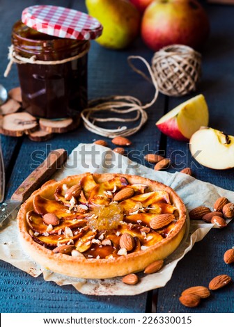 apple tart on a sand base with pear jam and caramel on dark wooden board