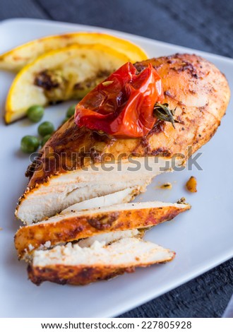incision baked chicken in a spicy curry sauce with vegetables,on a white plate