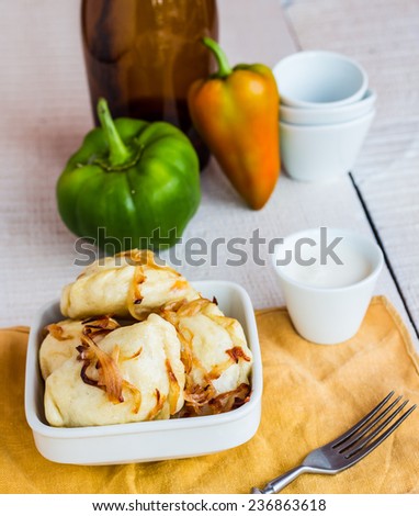 dumplings with potatoes, fried onions and sour cream, Ukrainian cuisine on a wooden board