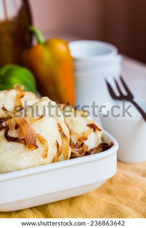 dumplings with potatoes, fried onions and sour cream, Ukrainian cuisine on a wooden board