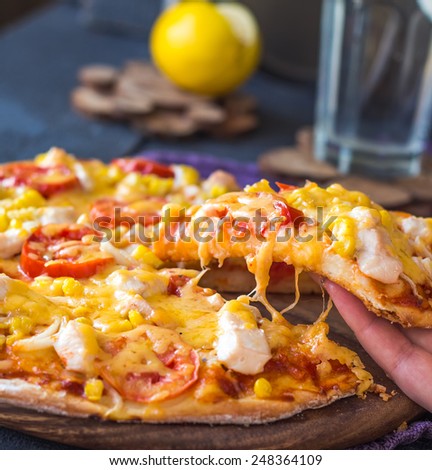 eating pizza with chicken, corn, tomatoes and cheese double, hands, kitchen Italy