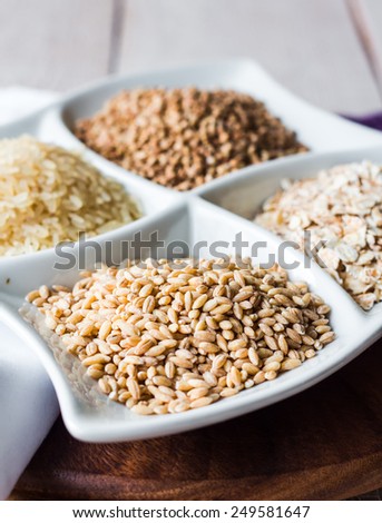 raw cereals, buckwheat, oats, pearl barley, white rice, garnish on a white plate