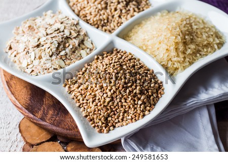 raw cereals, buckwheat, oats, pearl barley, white rice, garnish on a white plate