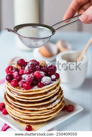 Pancake with cranberries, raspberries and powdered sugar, hands, American breakfast