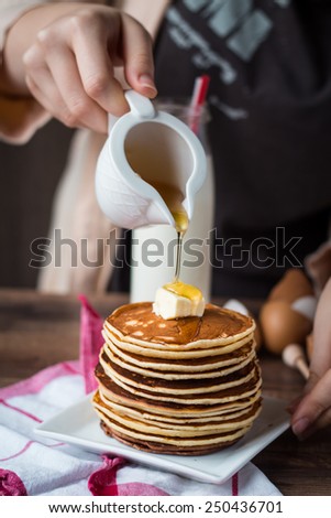 pile of Pancake with butter, pour honey, hand, American breakfast