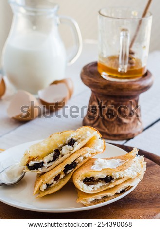 thin pancakes stuffed with cheese, prunes and sour cream, milk, breakfast, on a wooden board