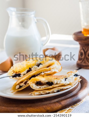 thin pancakes stuffed with cheese, prunes and sour cream, milk, breakfast, on a wooden board