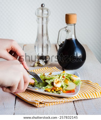 eating green salad with quail eggs, corn and apple, hand, fork and knife