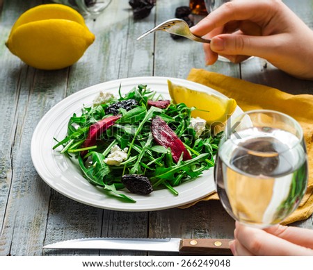eating green salad with arugula, beets, goat cheese and olive oil, hand, healthy food