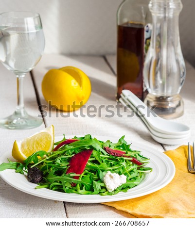 light green salad with arugula, beets, goat cheese and prunes, organic food on a white background