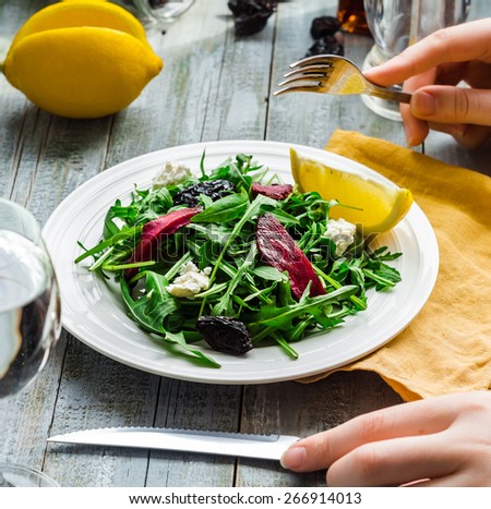 eating green salad with arugula, beets, goat cheese and olive oil, hand, healthy food